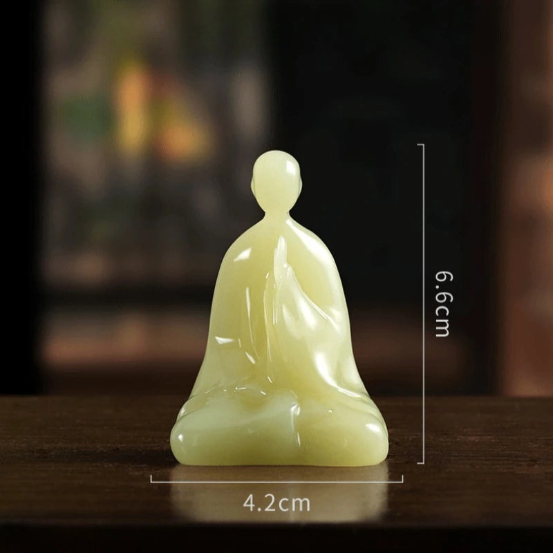 A small pale yellow-green seated figurine shown on a dark wooden surface with overlaid dimension lines indicating 4.2 cm width and 6.