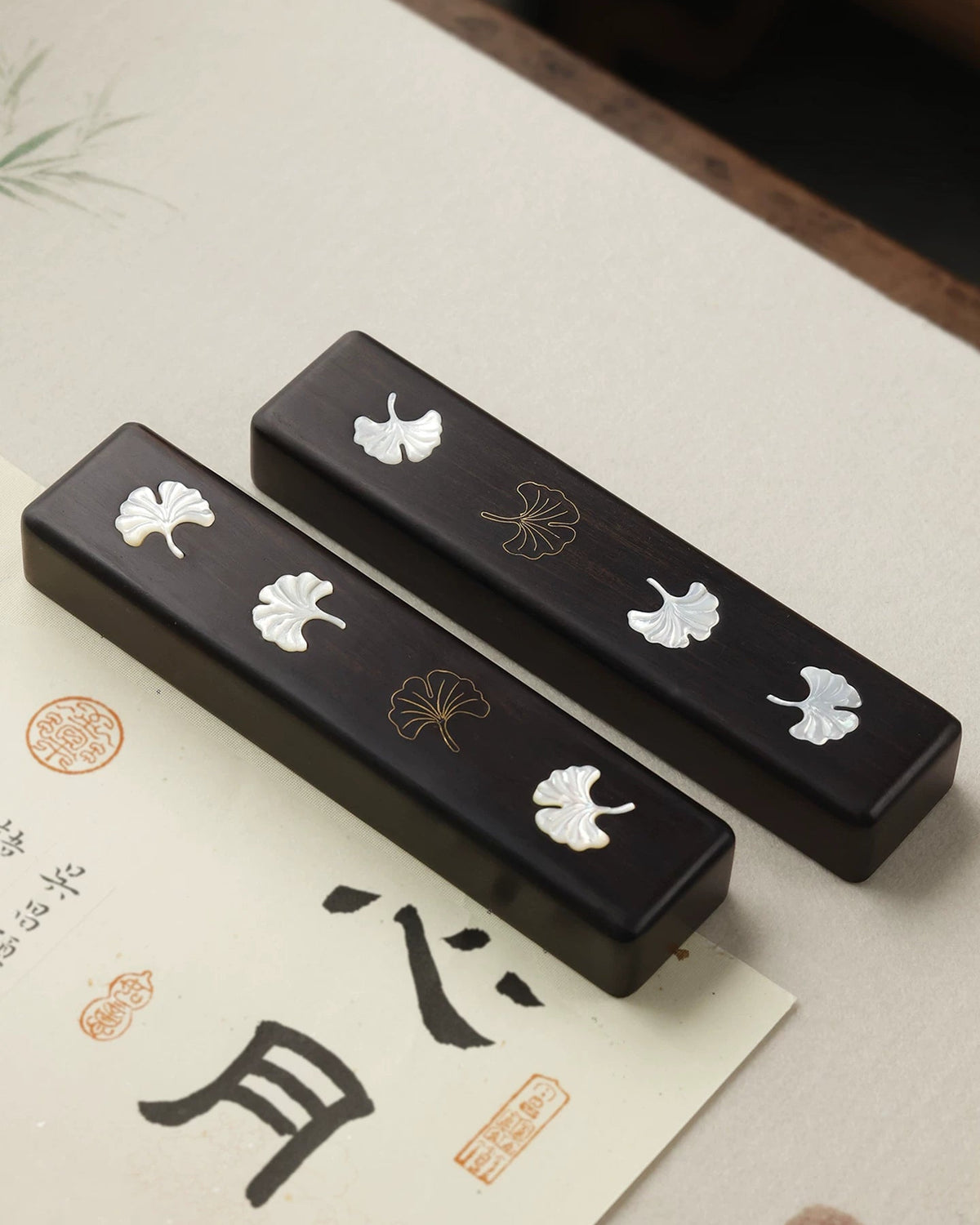 Pair of ebony Chinese calligraphy paperweights with white mother-of-pearl and brass ginkgo leaf inlay