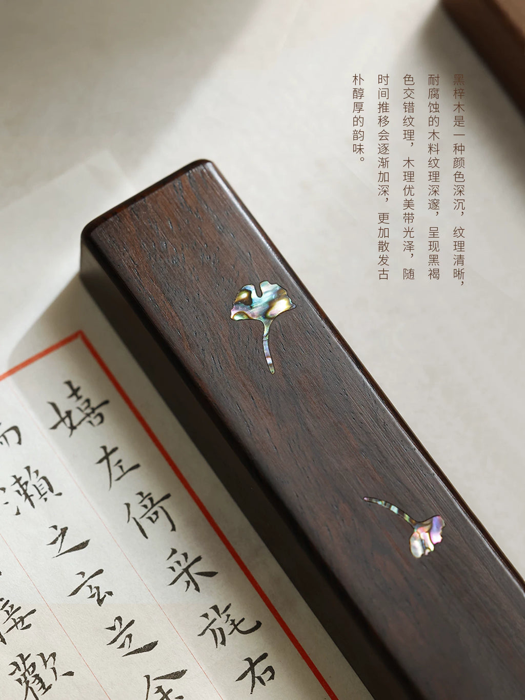 Close-up of wood grain and mother-of-pearl ginkgo leaf inlay on a Chinese calligraphy paperweight