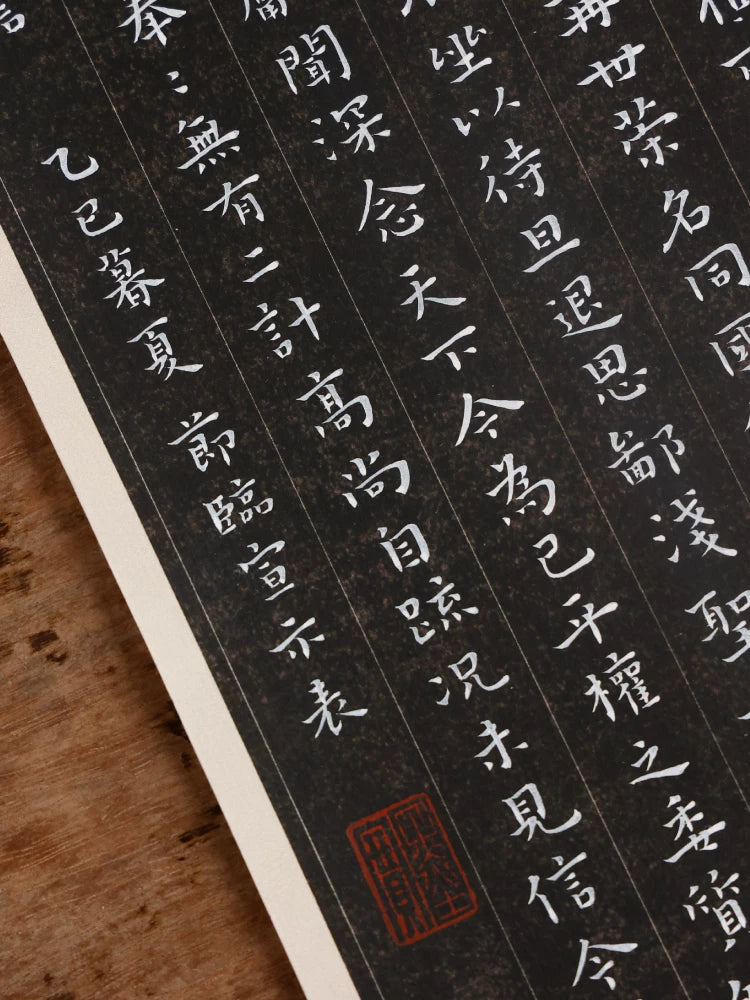 Close-up of white Chinese calligraphy in vertical columns on black paper with a red seal impression