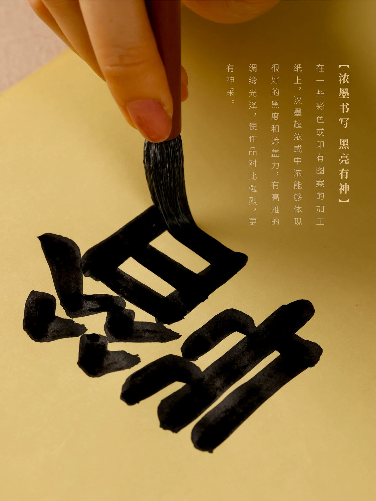Brush writing bold Chinese calligraphy strokes in black ink on gold-colored paper