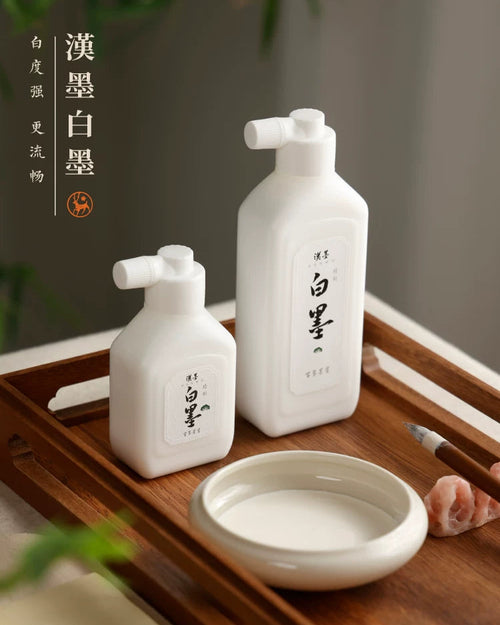 Hanmo Chinese calligraphy white ink bottles beside a dish of white ink and a brush on a wooden tray