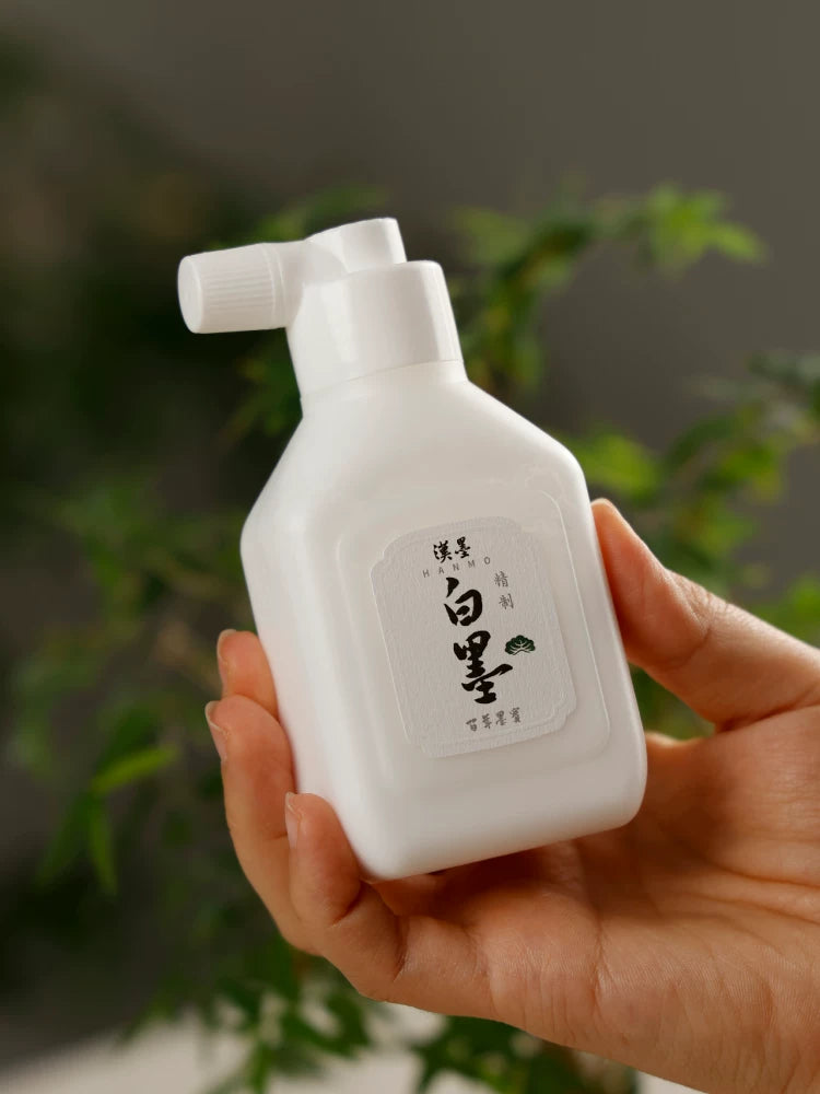 Hand holding a Hanmo Chinese calligraphy white ink bottle with a white dispensing cap