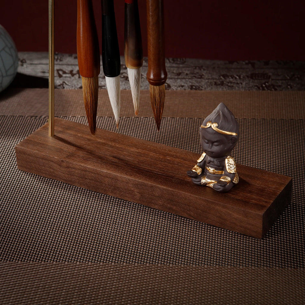 Metal brush rest with walnut base displayed in calligraphy desk setup
